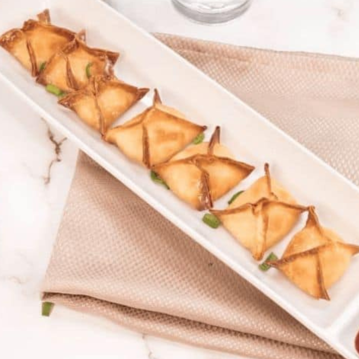 Air fryer basket with crab rangoon arranged inside, ready for cooking.