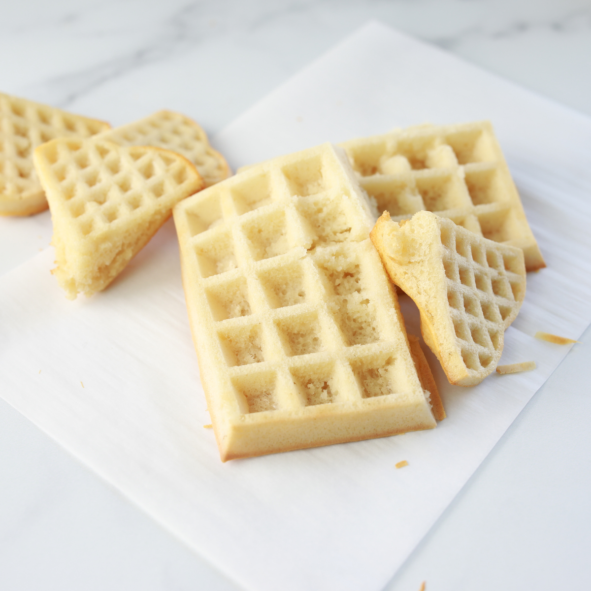 Golden brown homemade waffles cooked in the air fryer, served with syrup and fresh berries on a plate.