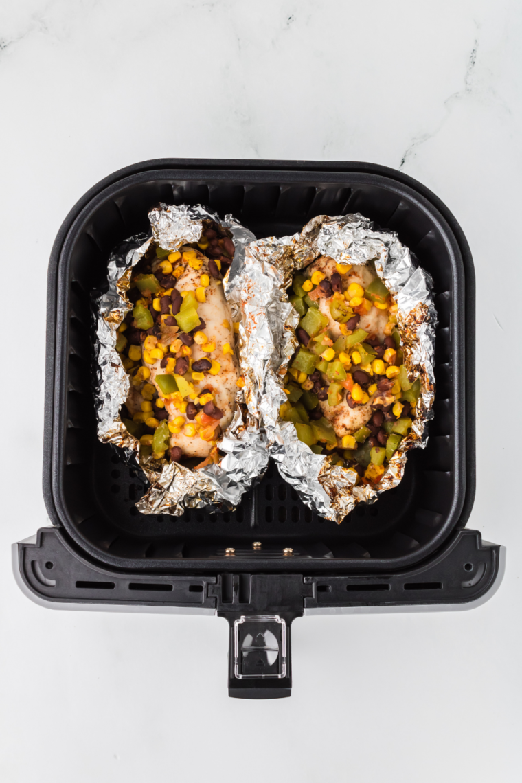 Opened foil packet showing the cooked chicken and melted cheese with veggies.