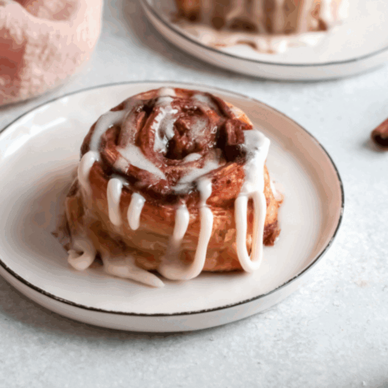 Golden pumpkin cinnamon rolls in air fryer topped with sweet glaze.