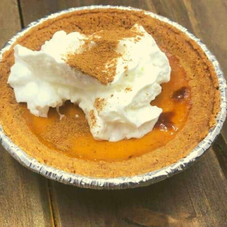 "A slice of Air Fryer Pumpkin Pie served on a plate, garnished with whipped cream."