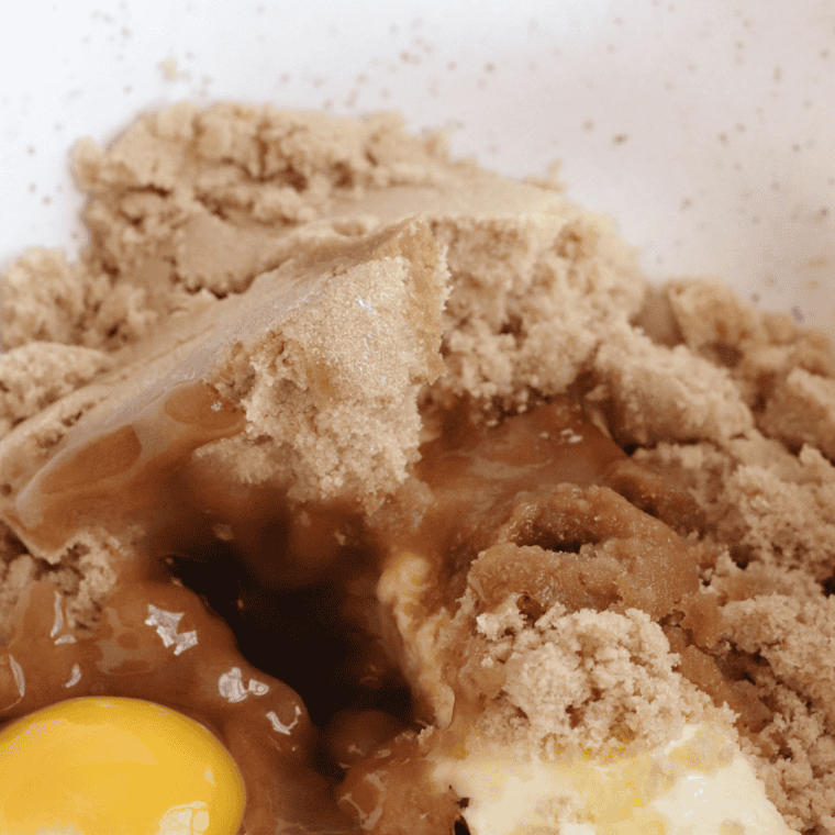 Beating sugars, eggs, vanilla, and folding chocolate chips into cookie dough.