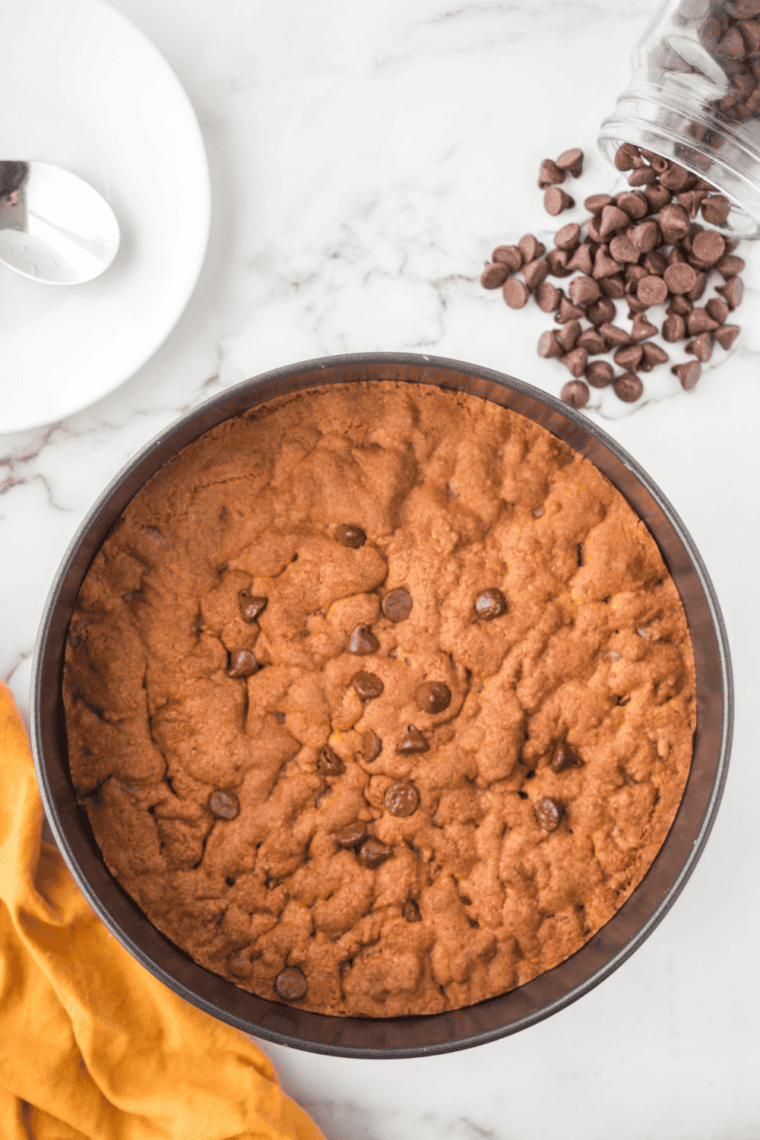 Freshly baked chocolate chip cookie bars in an air fryer-safe pan, golden brown and gooey.
