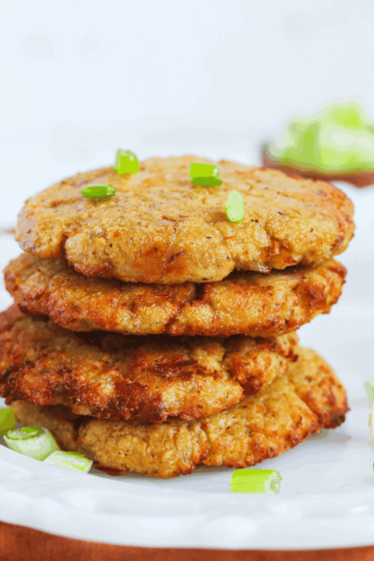 crispy air fryer tuna patties stacked on a plate with lemon wedges and dipping sauce