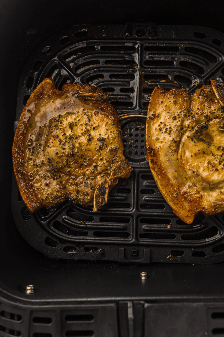 Air fryer Mexican pork chops seasoned with spices and garnished with lime and cilantro.