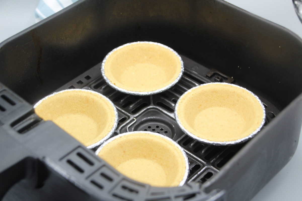 Start by taking out the pie crusts from the package and putting them in either the air fryer basket or air fryer tray. Set the temperature to 300 degrees F, air fryer setting, for 2 minutes. Check and make sure they are cooked before removing them.