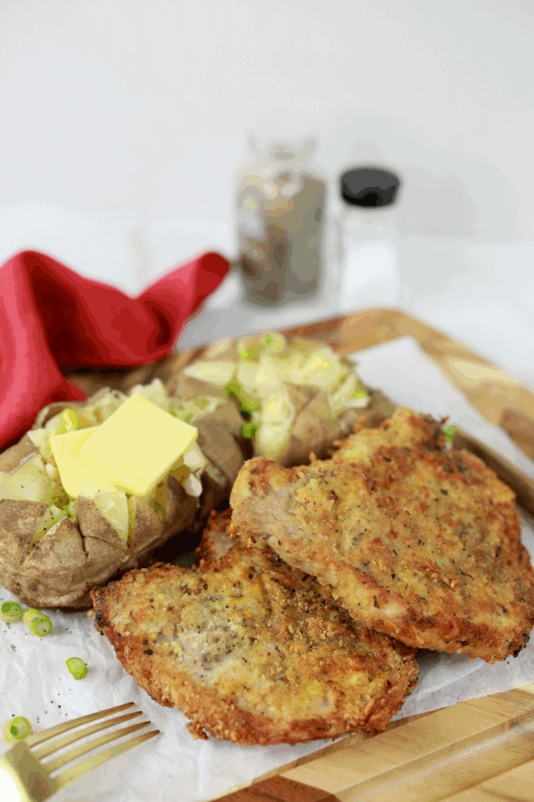 Crispy Outback Steakhouse style Parmesan crusted pork chops on a plate with lemon wedges and vegetables.
