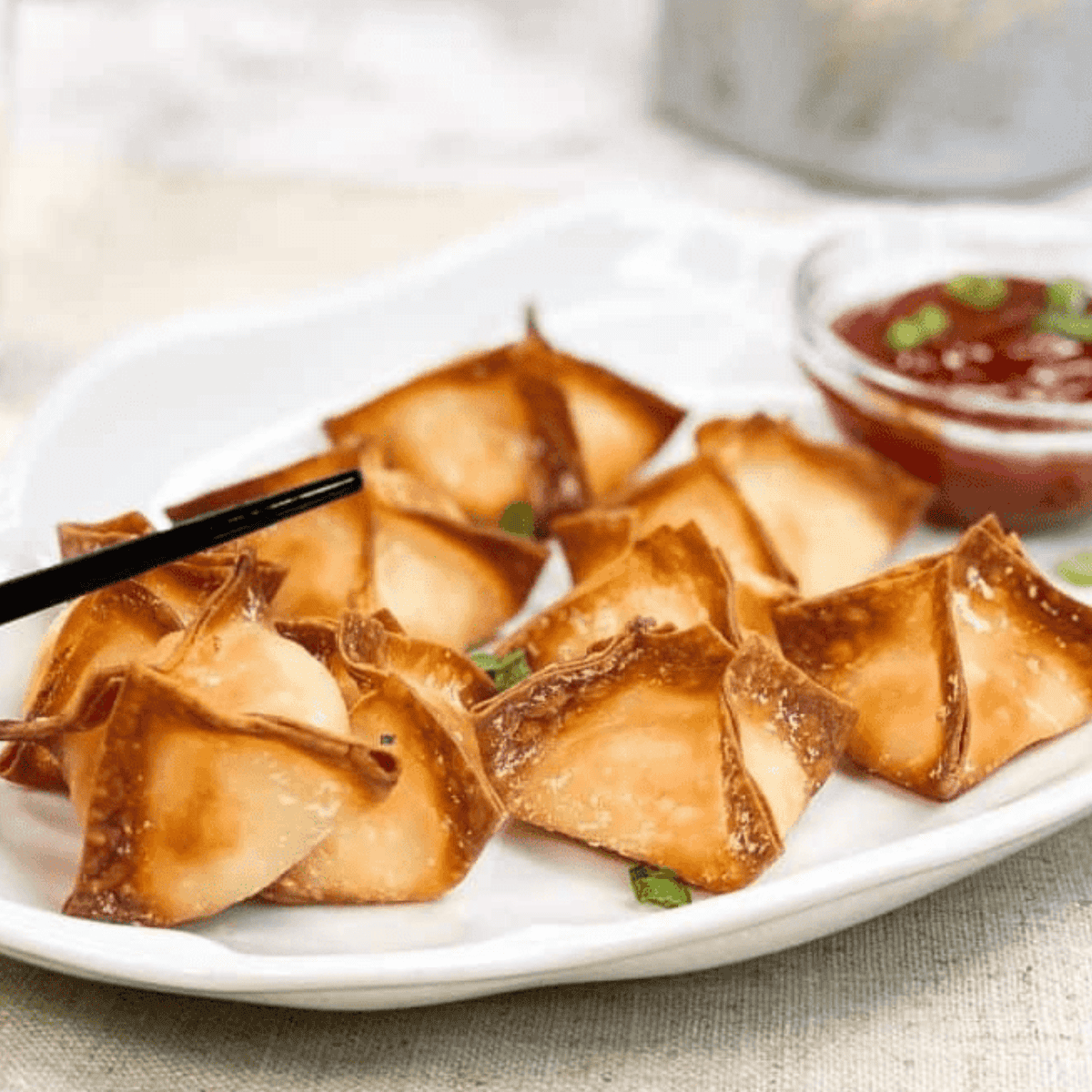 Golden, crispy P.F. Chang’s Crab Rangoons served on a plate with dipping sauce.