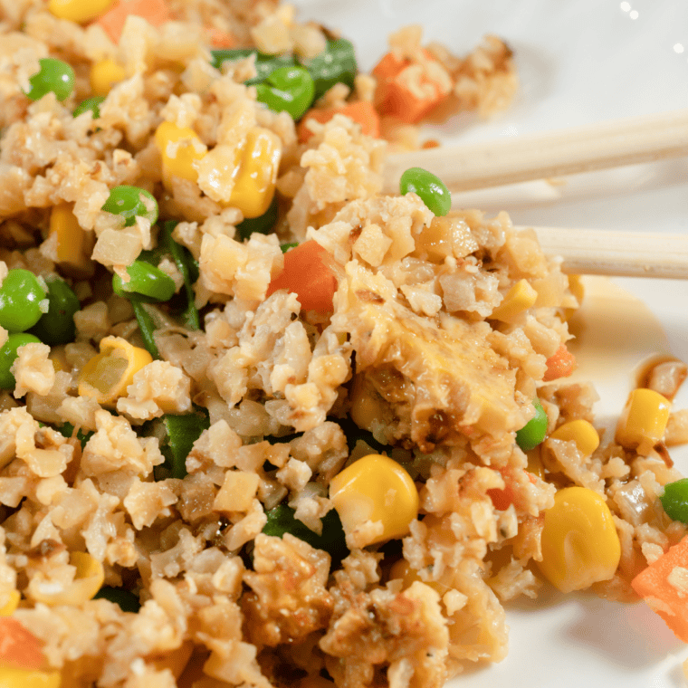 Bowl of golden air fryer fried cauliflower rice mixed with colorful vegetables, ready to serve