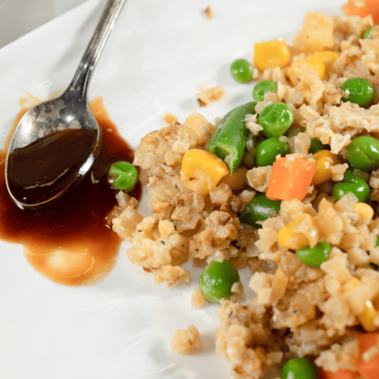 Air fryer fried cauliflower rice with vegetables, cooked to golden perfection and served in a white bowl