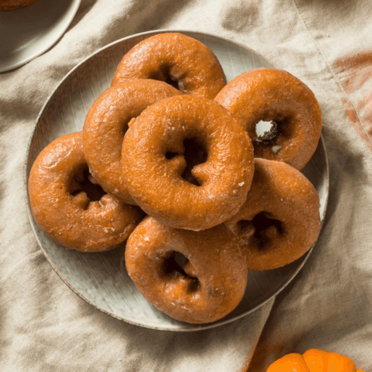 Golden Easy Air Fryer Pumpkin Donuts coated with cinnamon sugar on a plate.