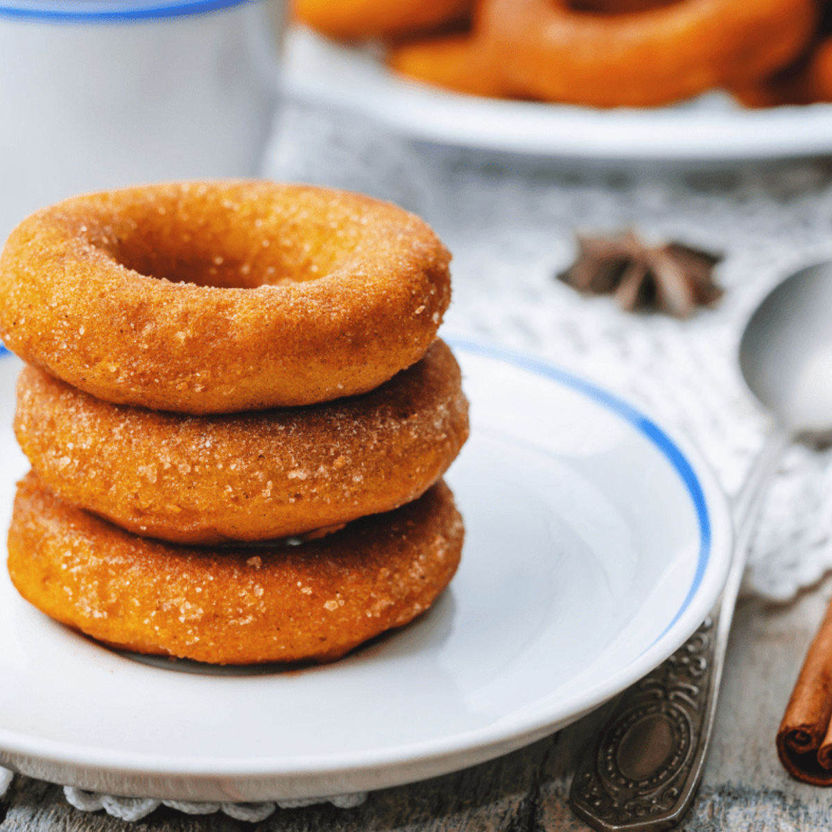 Golden Easy Air Fryer Pumpkin Donuts topped with cinnamon sugar on a plate.
