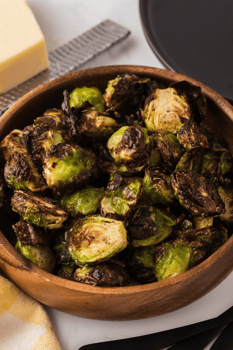 Air fryer crispy Brussels sprouts with smoky maple syrup and red pepper flakes, served with a flavorful sauce.