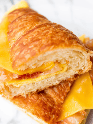 Air fryer bacon egg and cheese croissant cut in half showing candied bacon, a fried egg, and melted cheese