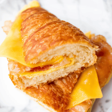 Air fryer bacon egg and cheese croissant cut in half showing candied bacon, a fried egg, and melted cheese