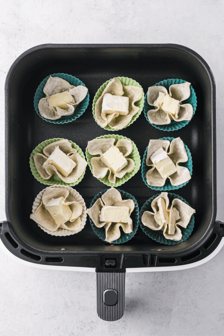 Placing a cube of brie cheese into a wonton wrapper.