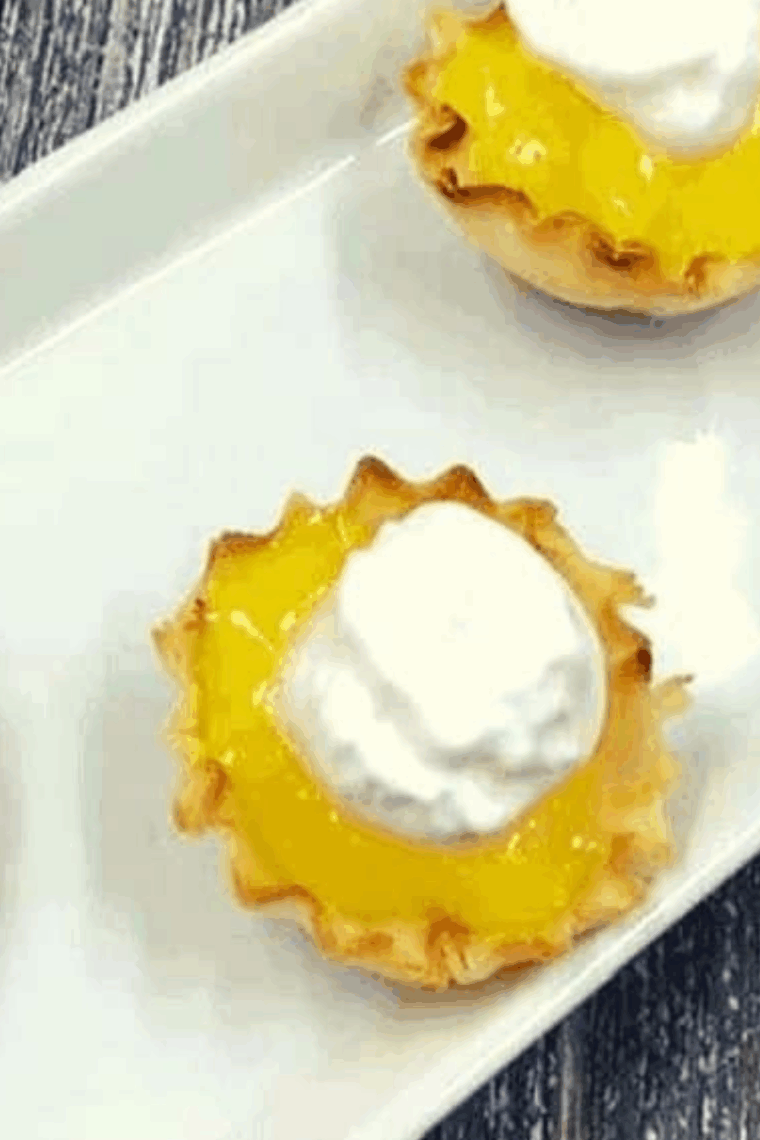 Air Fryer Mini Lemon Tarts in golden phyllo shells topped with whipped cream.