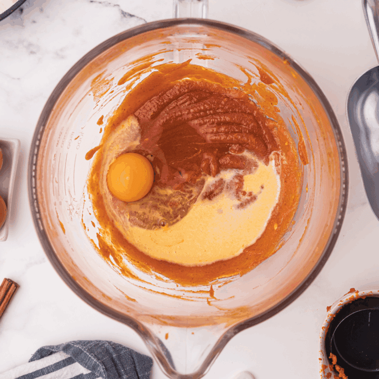 Whisking sugars, pumpkin puree, vegetable oil, eggs, and vanilla in a mixing bowl