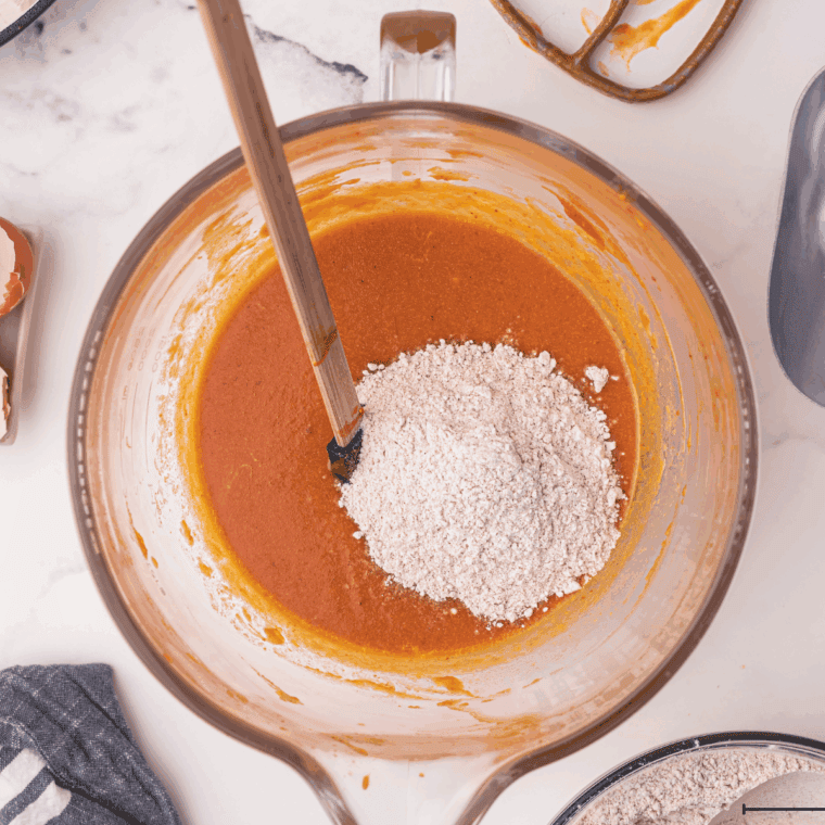 Folding dry ingredients into wet pumpkin bread batter with a spatula