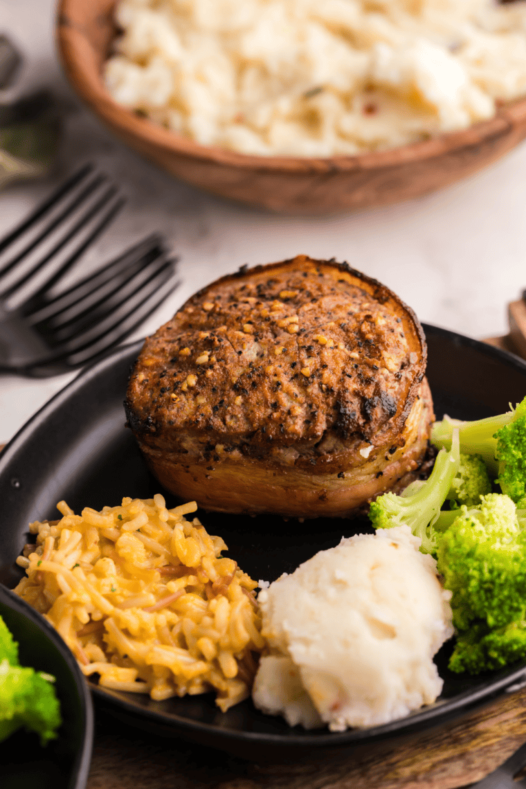 Air fryer bacon-wrapped filet mignon on a plate, crispy bacon and perfectly cooked steak ready to serve.