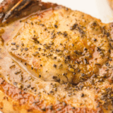 Golden brown BJ’s style pork chops served with sides on a plate