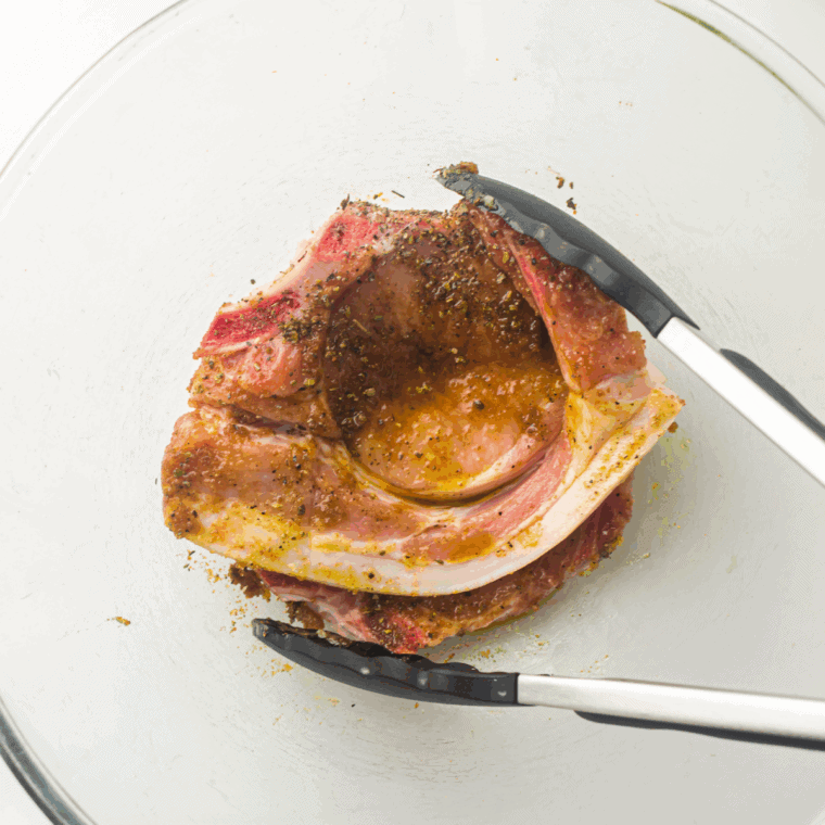 Season boneless pork chops with olive oil, garlic, onion powder, paprika, salt, and pepper.