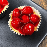 Plate of air fryer cherry cheesecake cupcakes topped with cherry pie filling