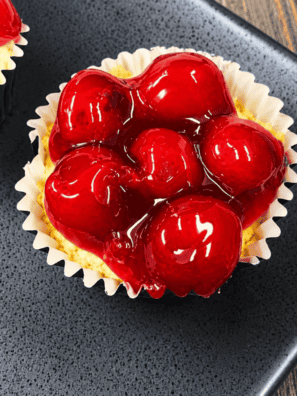 Plate of air fryer cherry cheesecake cupcakes topped with cherry pie filling