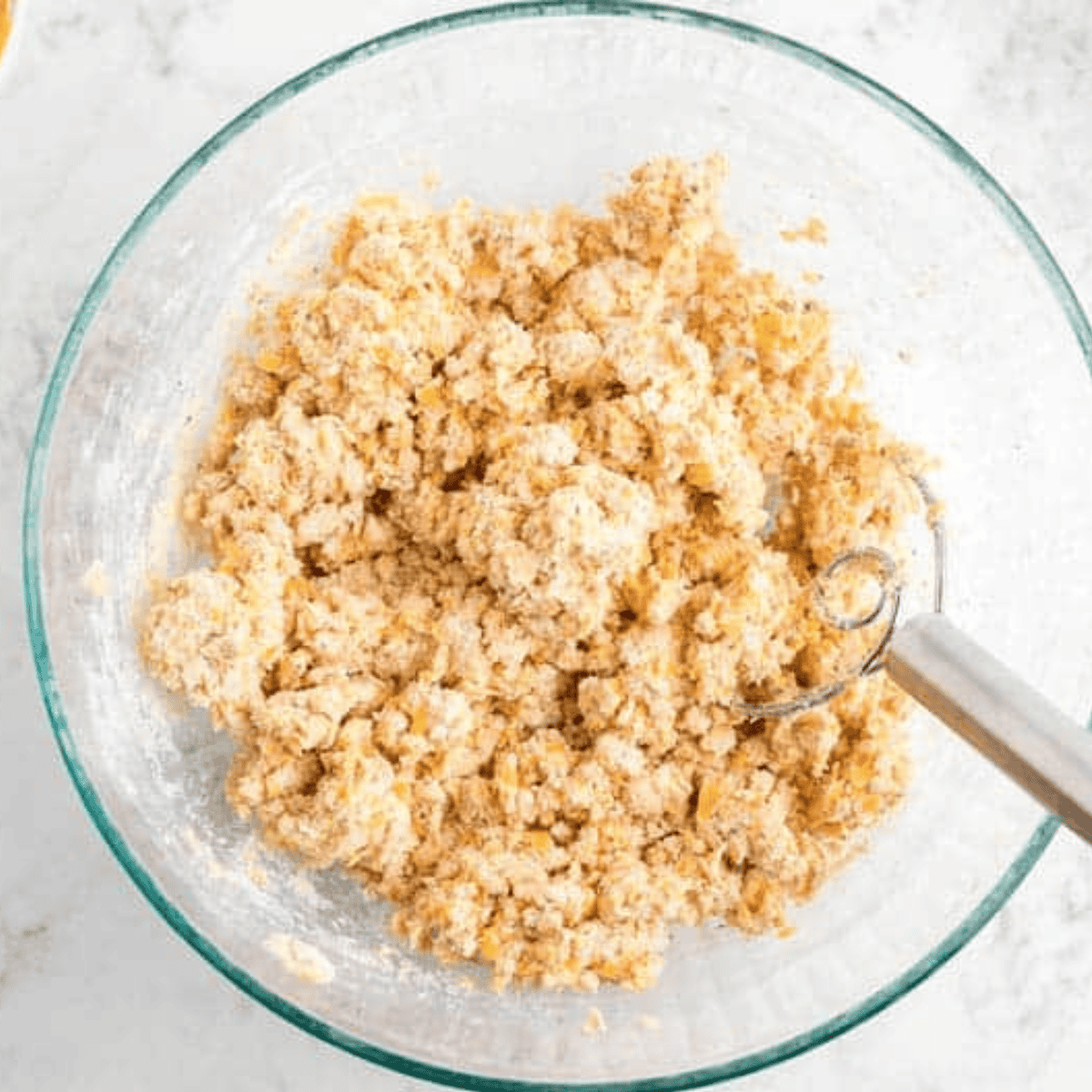 Mixing wet and dry ingredients separately in two bowls, then combining with shredded cheese using a wooden spoon.