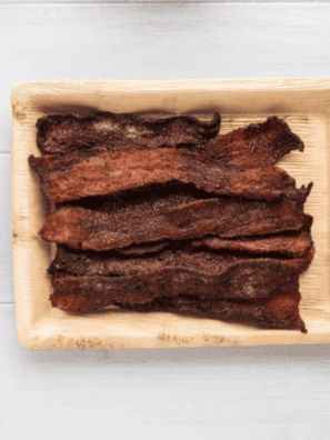 Golden, crispy Air Fryer Millionaire’s Bacon glazed with caramelized sweetness, served on a parchment-lined plate.