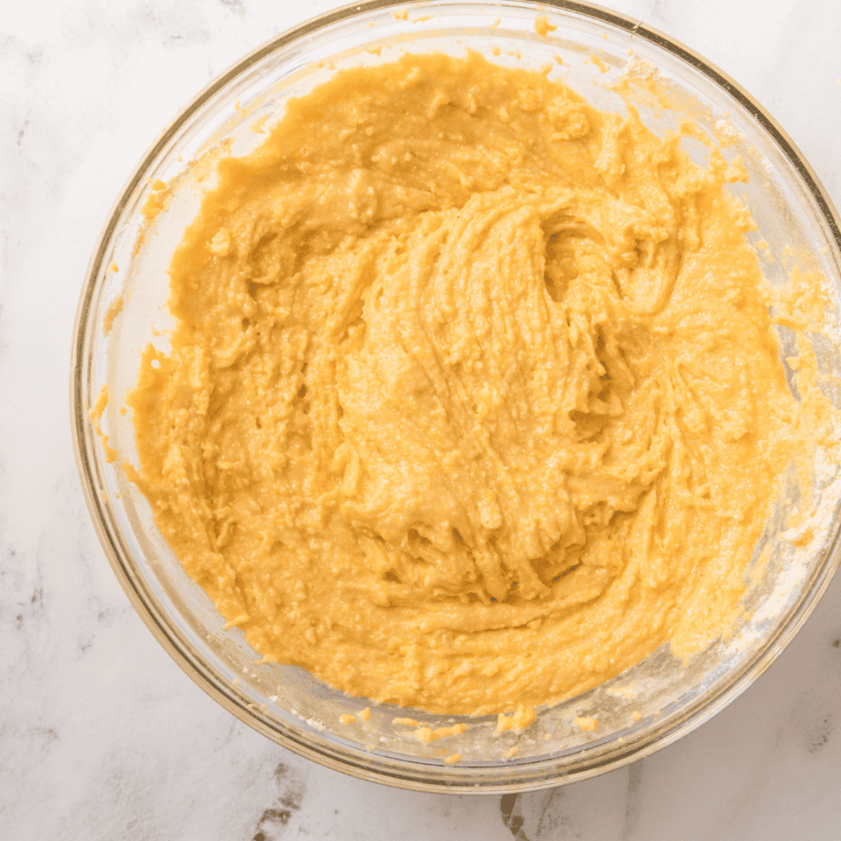 Folding corn kernels into cornbread batter once wet and dry ingredients are mixed.
