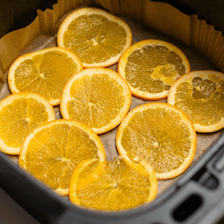 Arranging orange slices in a single layer on the air fryer basket, avoiding overlap for proper airflow.