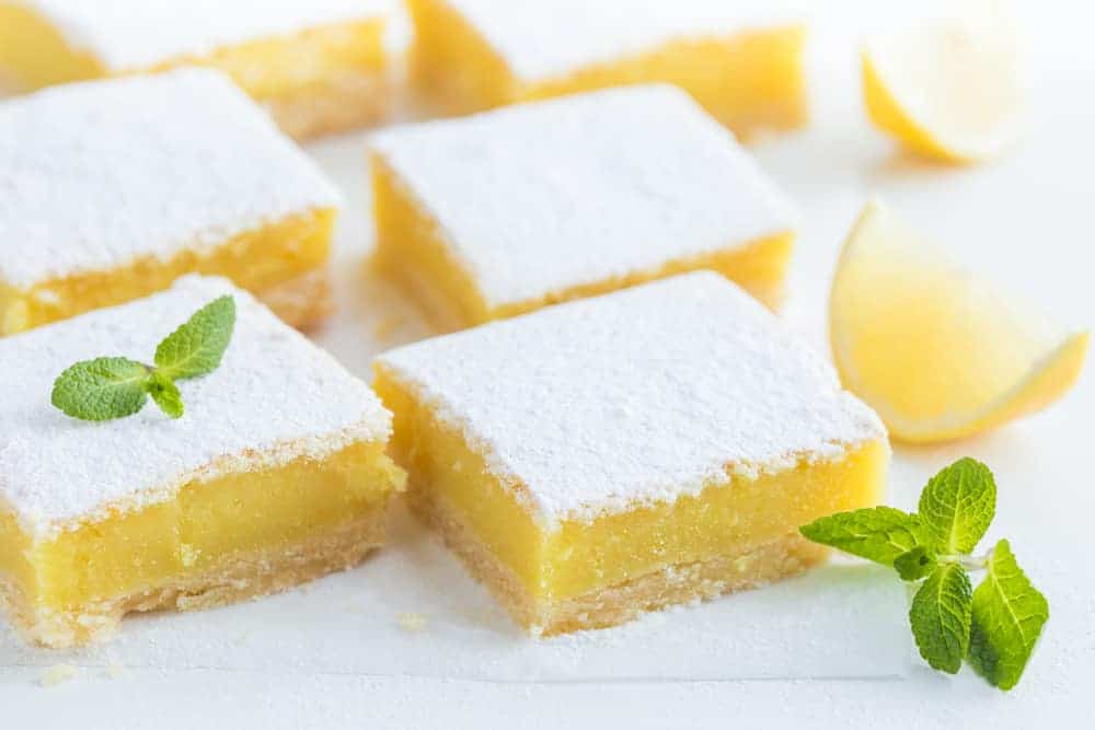 freshly baked lemon bars (or lemon  squares) with powdered sugar on white bakground, selective focus