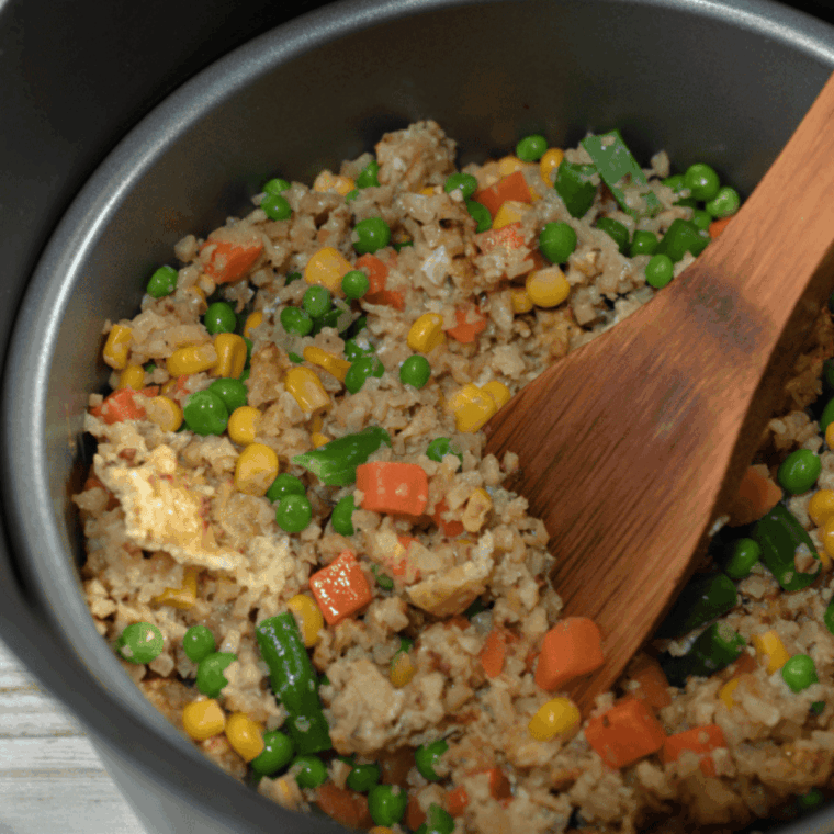 Cook the Veggies: Vegetables tossed in sesame oil cooking in the air fryer basket