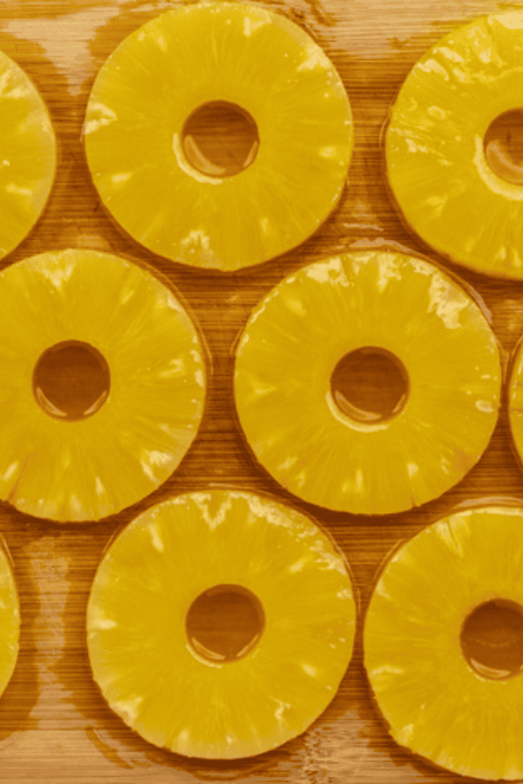 Pineapple rings being brushed with a smooth honey glaze coating.