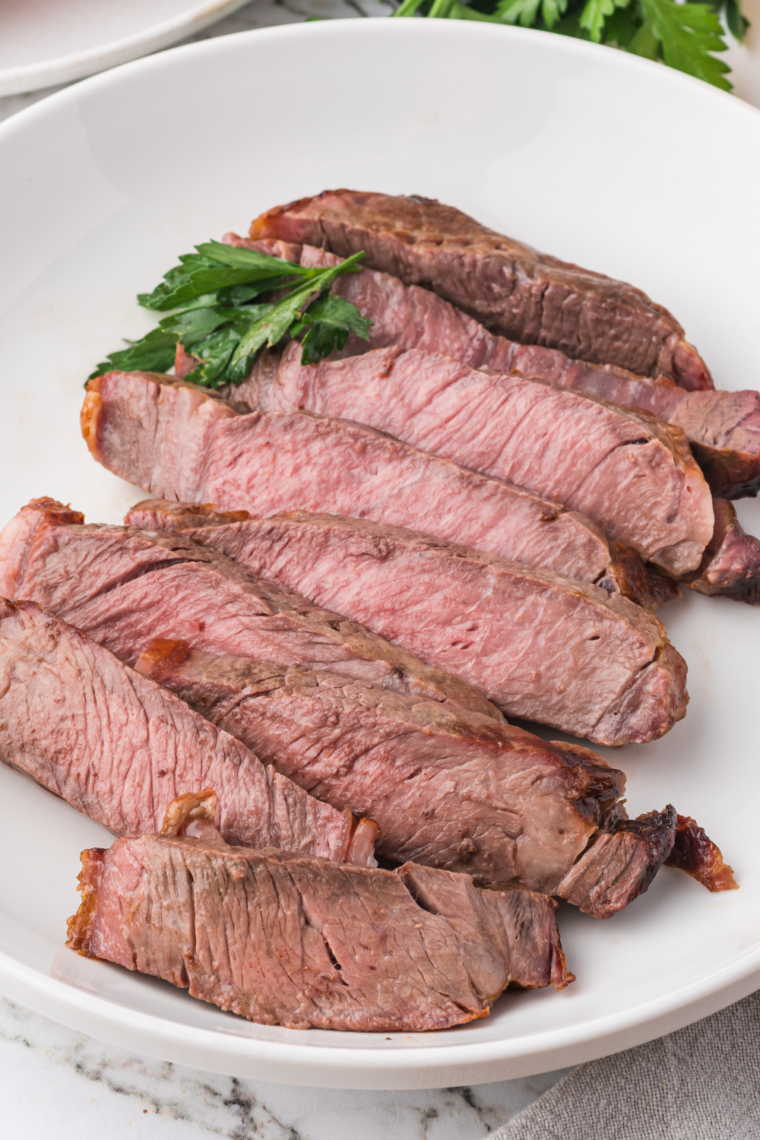 Ninja Crispi steak sliced against the grain on parchment, showing an even medium-rare center