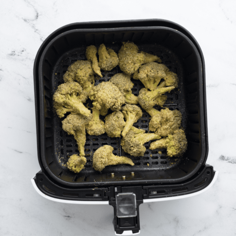 Air fryer basket loaded with breaded broccoli, ready to cook.