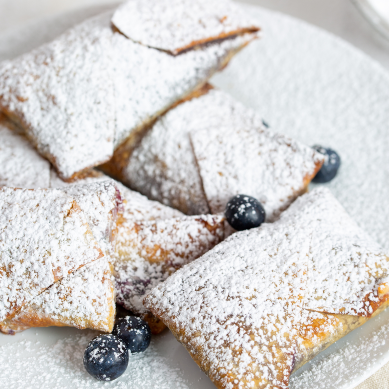 Overhead view of blueberry egg rolls on a plate with powdered sugar