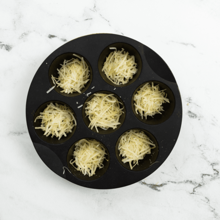 Shredded cheese crisps browning to golden in the air fryer at 375 degrees