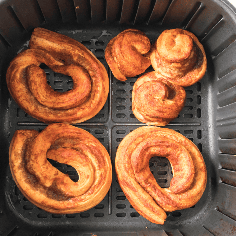 Drizzling icing over freshly air-fried cinnamon roll donuts while still warm