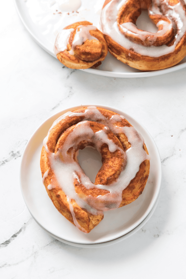 Close up picture of cinnamon roll donuts on a white plate.