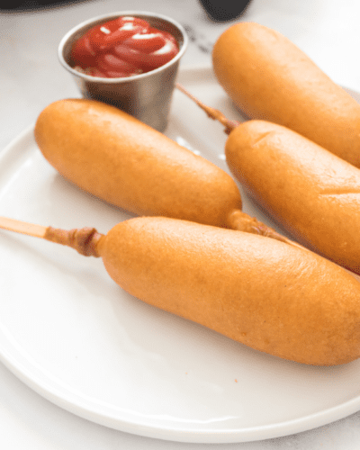 air fryer corn dogs on a plate with a side of ketchup