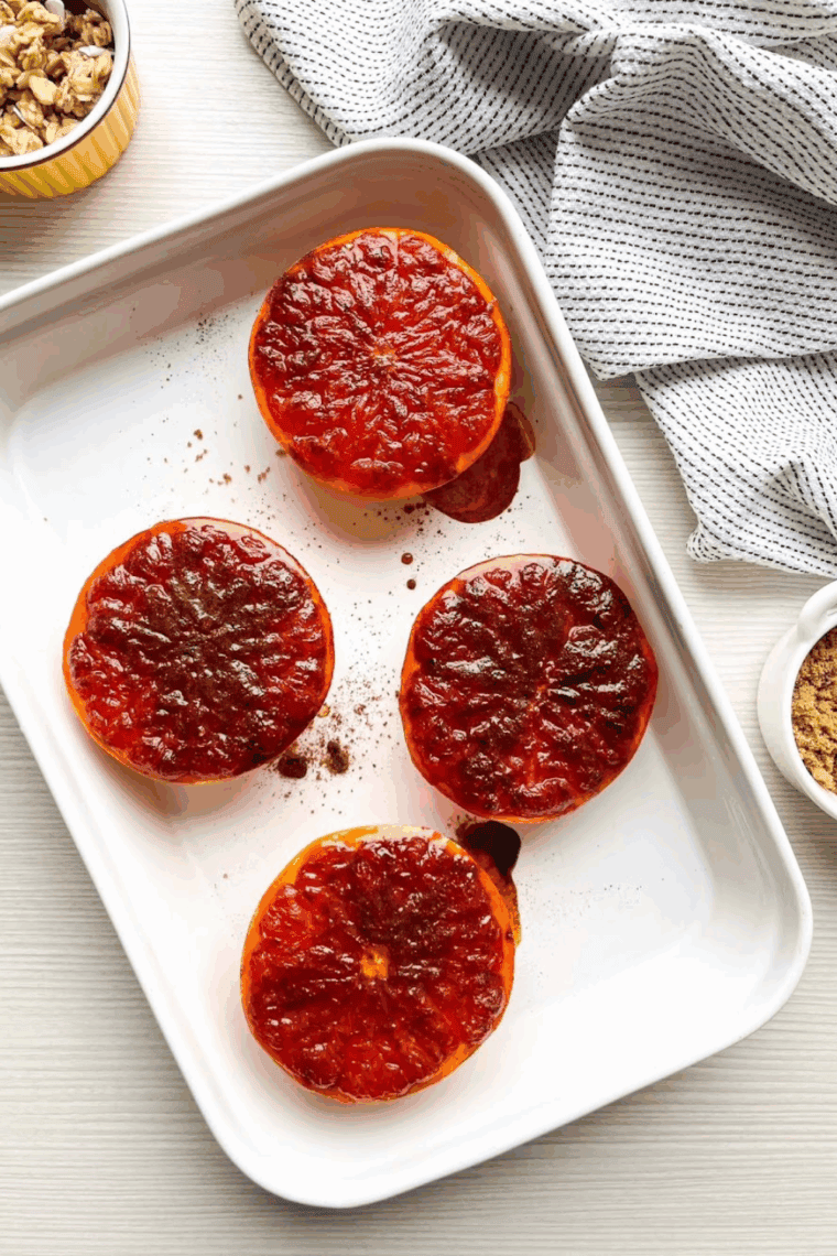 Caramelized air fryer grapefruit halves with golden browned tops on a white plate.