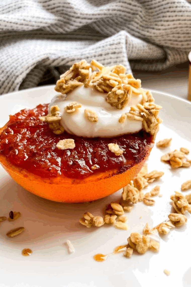 Caramelized air fryer grapefruit halves sprinkled with cinnamon and brown sugar, served with a dollop of Greek yogurt and granola.