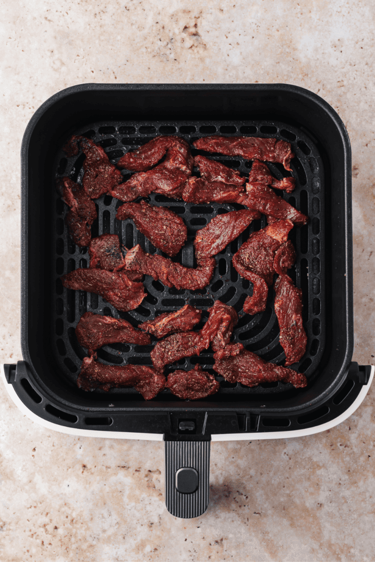 Cooking Air Fryer Parmesan Crusted Steak in the air fryer basket.