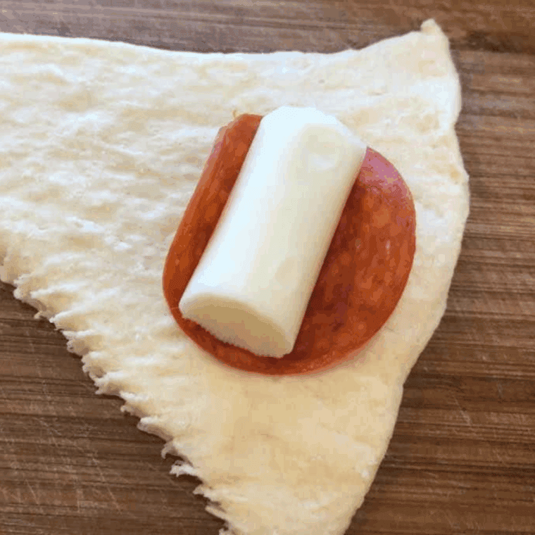 Add the cheese stick and pepperoni slice on top of the biscuit dough.