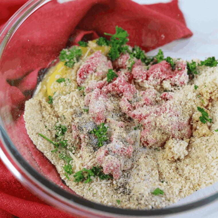 Combining ground Italian sausage, breadcrumbs, Parmesan, and seasonings in a bowl to prepare meatball mixture.