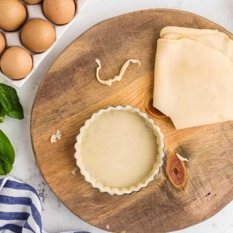 Placing the pie dough into the tart pan, pressing firmly.