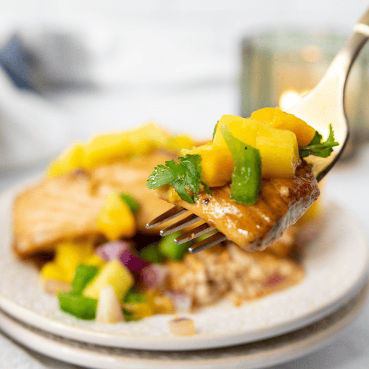Air fryer cooked swordfish steak served with fresh mango salsa and garnished with cilantro.