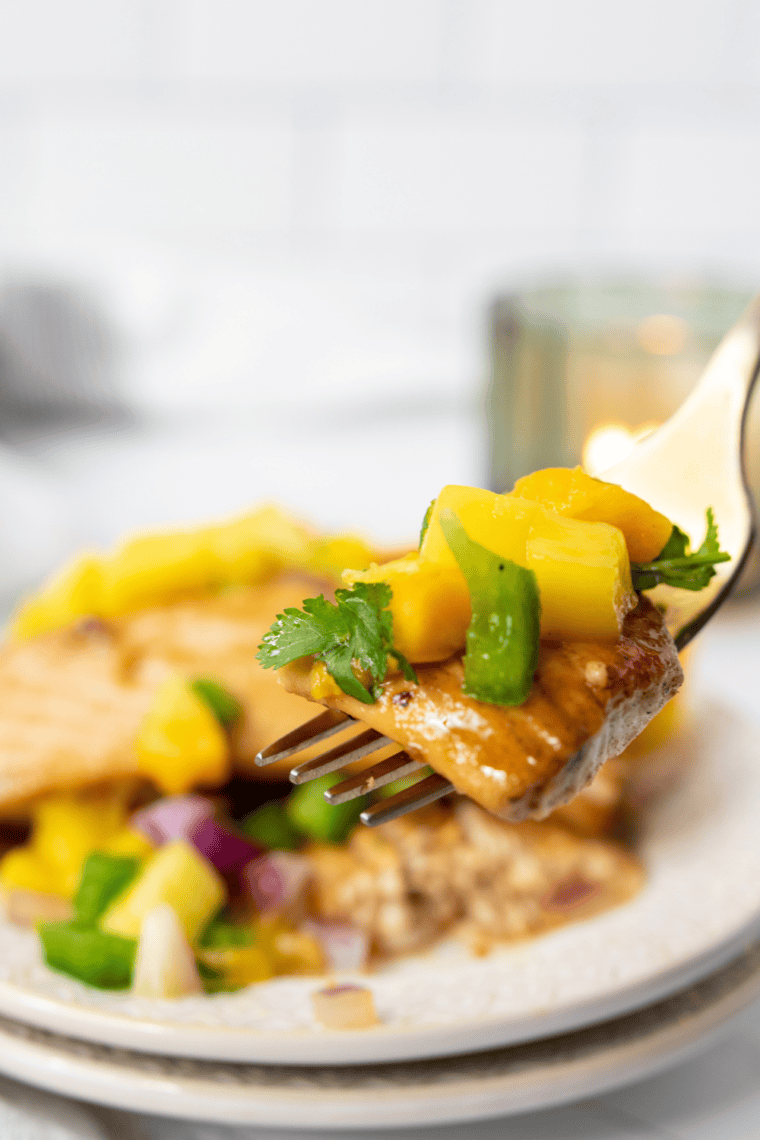 Juicy air fryer swordfish steak served with fresh mango salsa and garnished with herbs.